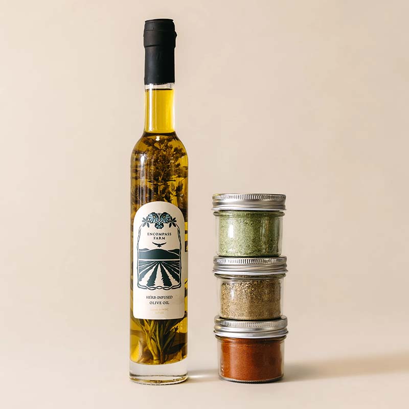 bottle of infused olive oil next to three jars of seasoning blends