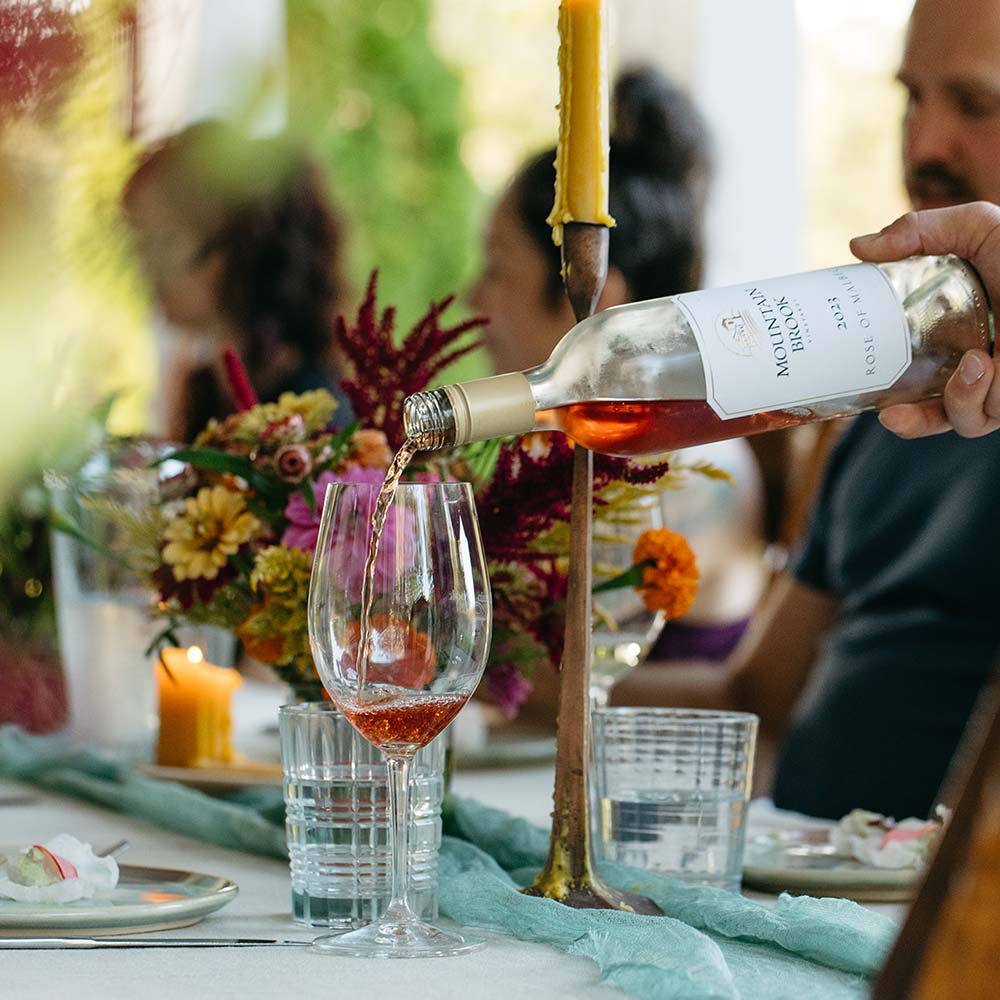 Person pouring wine into a glass at a table with a blurred background