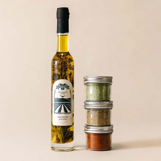 bottle of infused olive oil next to three jars of seasoning blends