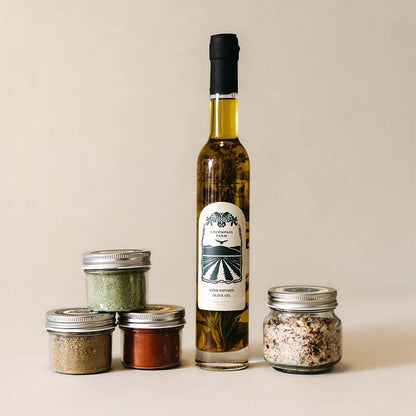 bottle of infused olive oil next to three jars of seasoning blends and a jard of finishing salt