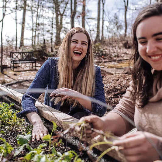 two women planting in a raised garden bed